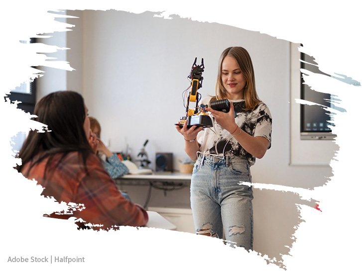 Schülerin präsentiert stolz einen Roboter vor der Klasse