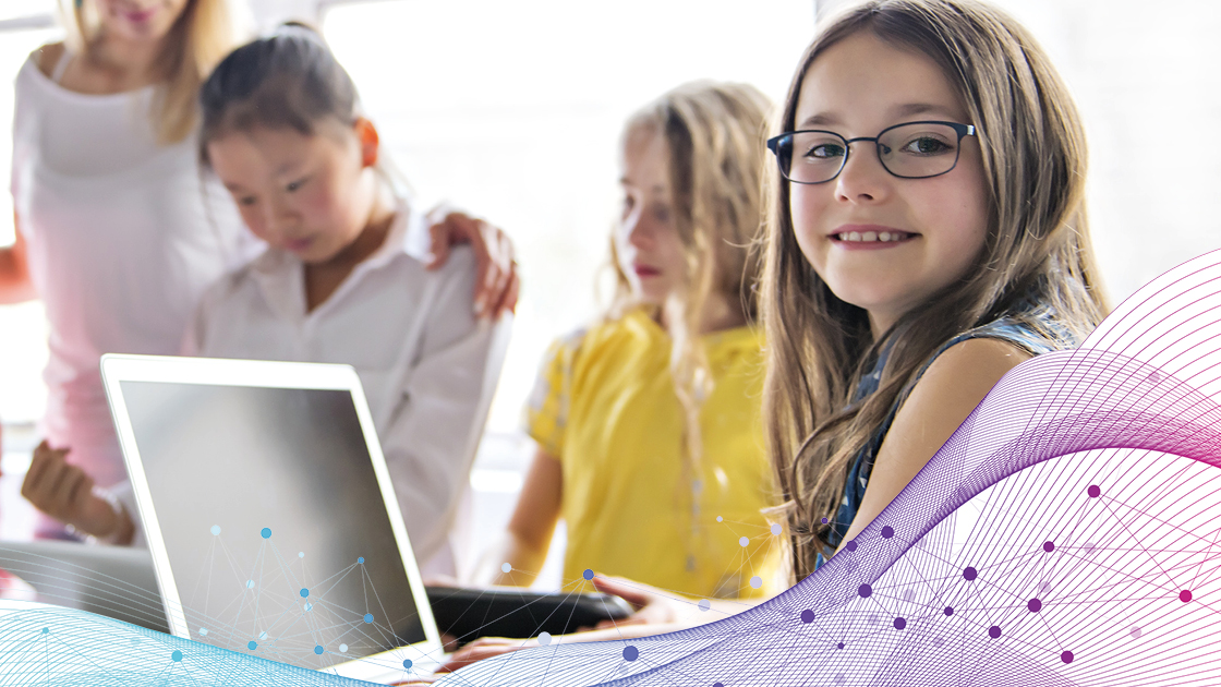 Fröhliches Mädchen sitzt vor einem Computer in einem Klassenzimmer