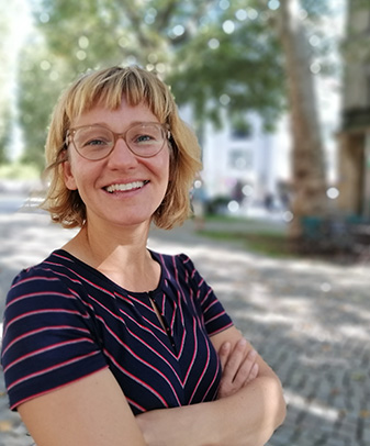 Porträt einer lächelnden Frau mit Brille und verschränkten Armen
