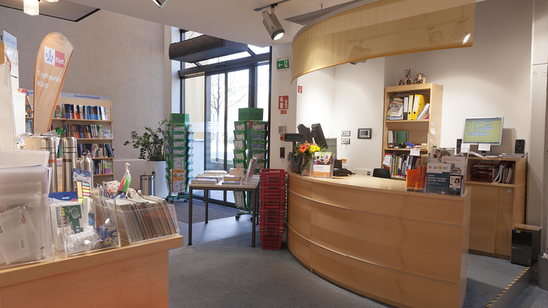 Laden „Treffpunkt Klett“ mit Bücherregalen, Einkaufskörben und Kassentheke