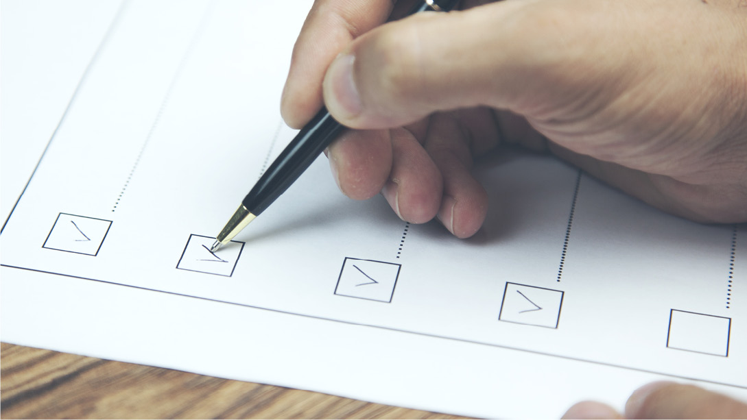 Eine Person füllt ein Formular aus, indem sie mit einem Stift Kästchen einer Checkliste ankreuzt