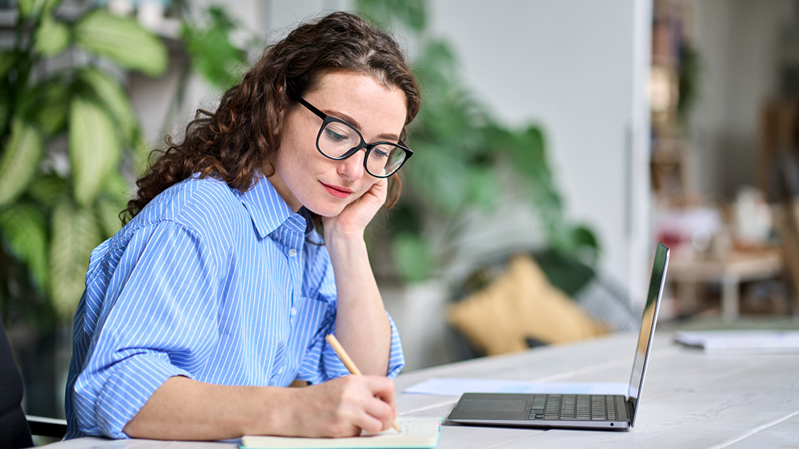 junge Lehrerin am Laptop mit Block und Stift junge Lehrerin am Laptop mit Block und Stift