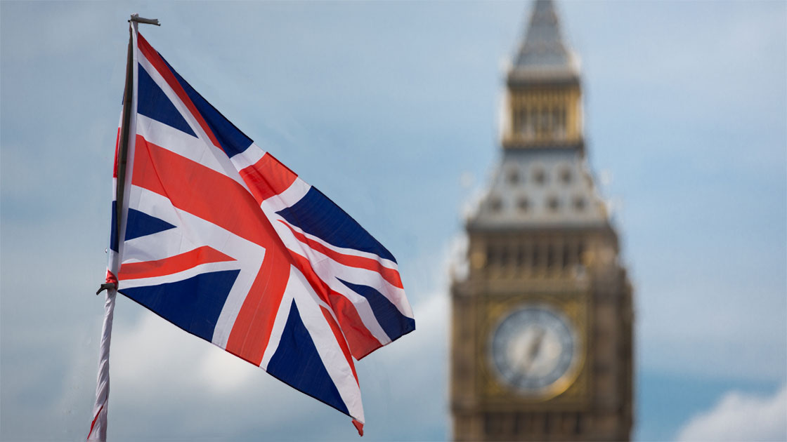 Eine Flagge von Großbritanninen, im Hintergrund der Uhrturm „Elizabeth Tower“, auch „Big Ben“, in London Eine Flagge von Großbritanninen, im Hintergrund der Uhrturm „Elizabeth Tower“, auch „Big Ben“, in London