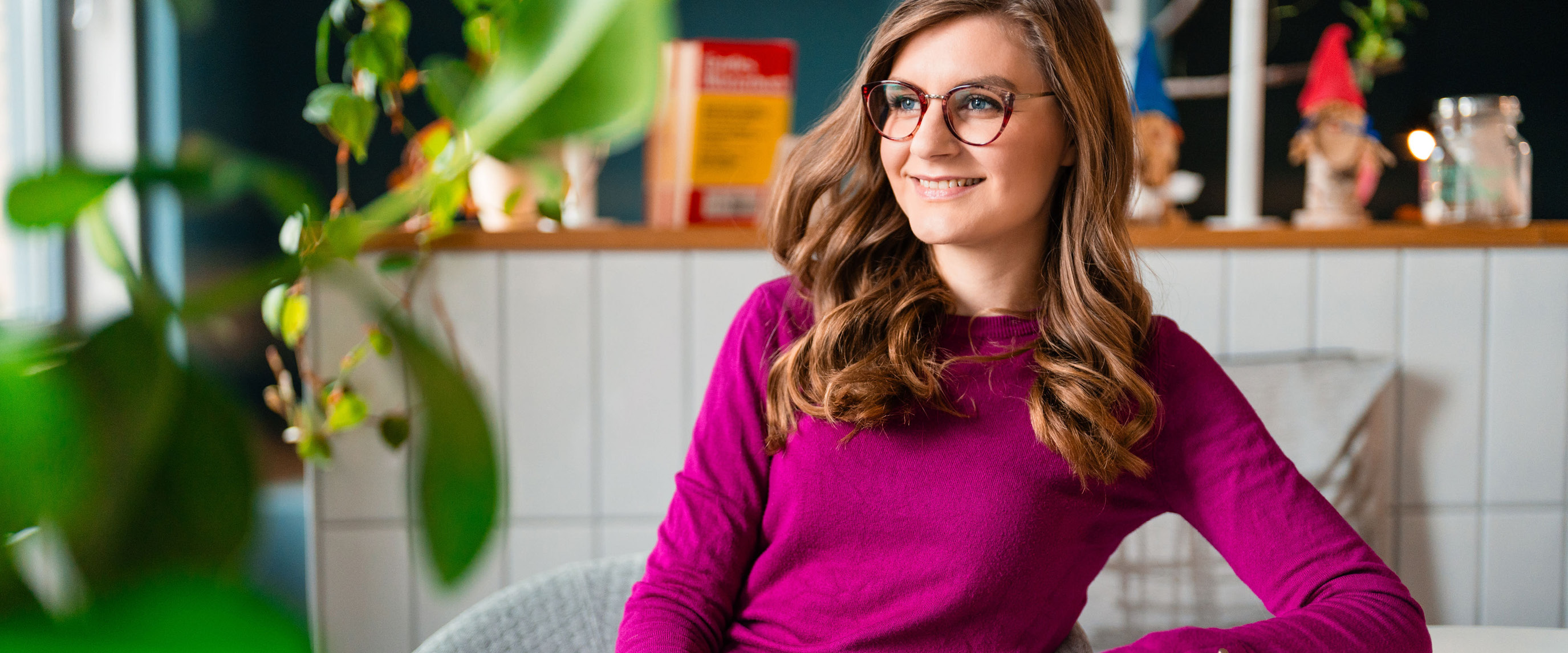 Lehrerin mit Brille sitzt auf einem Stuhl lächelt zur Seite