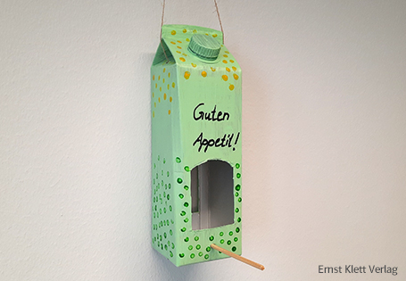 Vogelhaus aus gebasteltem Getränkekarton mit der Aufschrift „Guten Appetit!“ 
