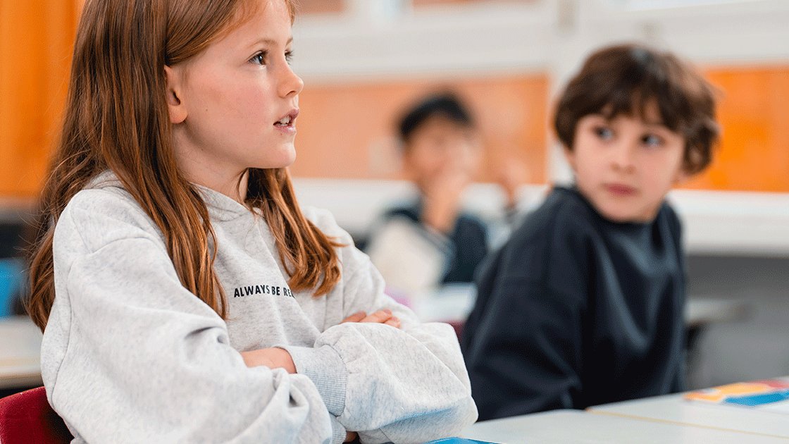 Ein Mädchen und ein Junge sitzen in einem Klassenzimmer. Das Mädchens schaut nach vorne, der Junge schaut zur Seite. Ein Mädchen und ein Junge sitzen in einem Klassenzimmer. Das Mädchens schaut nach vorne, der Junge schaut zur Seite.