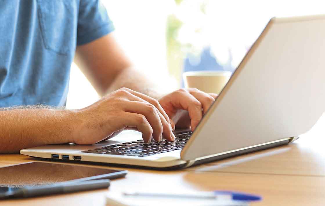 Mann tippt auf der Tastatur seines Laptops