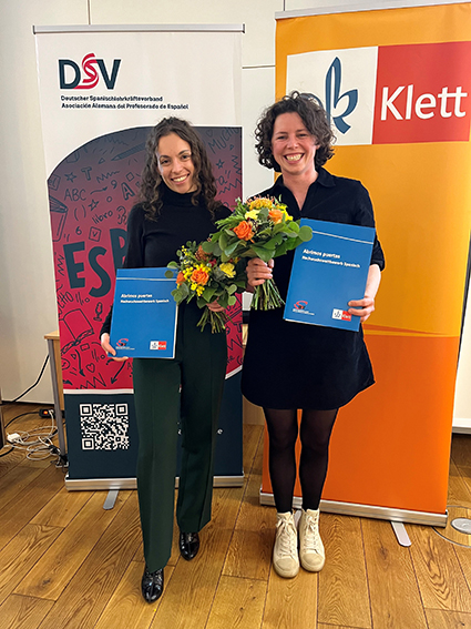 Drei Preisträgerinnen mit Urkundenmappen und Blumensträußen