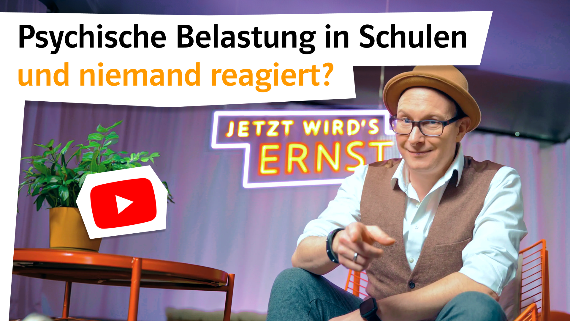 Matthias Zeitler sitzt auf Stuhl im Foto-Studio und zeigt mit Finger nach vorne in die Kamera.