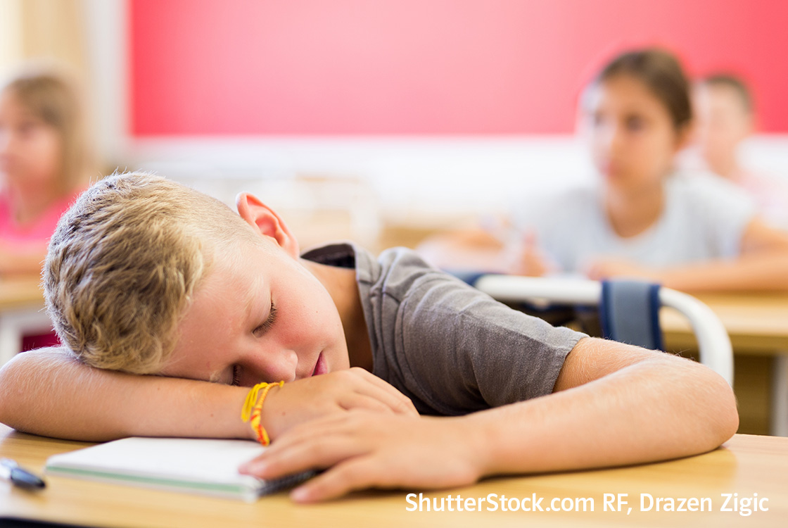 Ein schlafender Junge liegt mit seinem Kopf auf seinem Tisch. Ein schlafender Junge liegt mit seinem Kopf auf seinem Tisch.