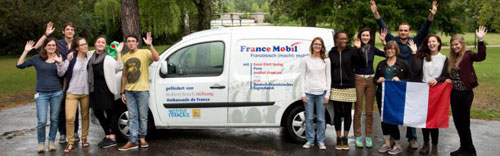 Eine Gruppe von Personen steht mit einer Frankreich Flagge vor einem weißen Lieferwagen