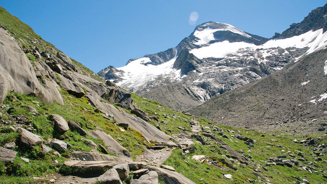 Eine felsige Berglandschaft mit einer mit Schnee bedeckten Bergspitze im Hintergrund Eine felsige Berglandschaft mit einer mit Schnee bedeckten Bergspitze im Hintergrund