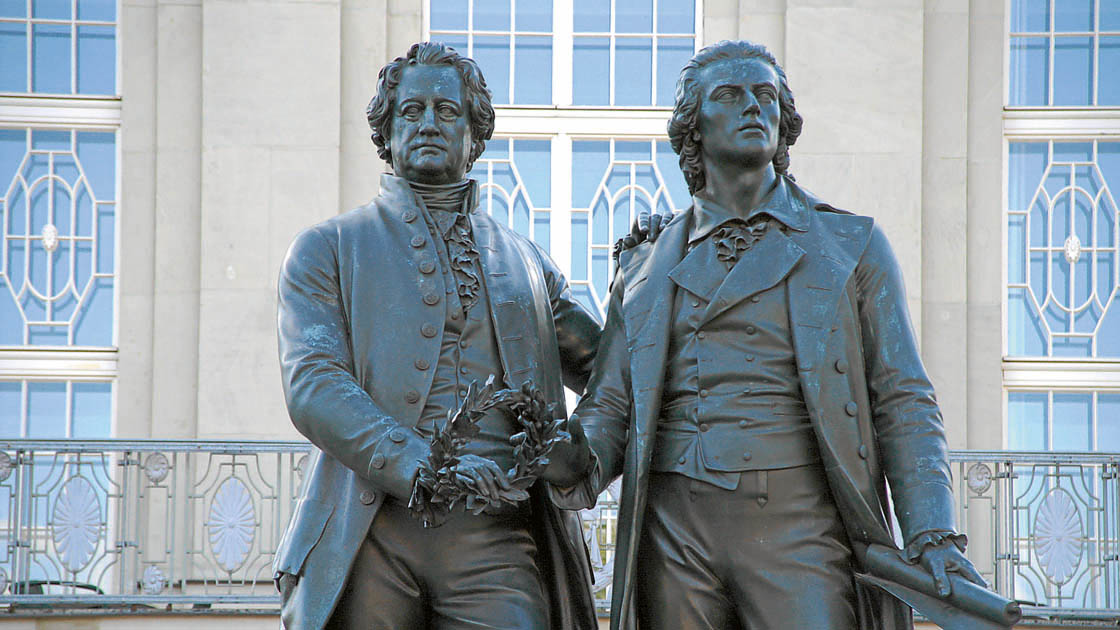 Bronzestatue der deutschen Dichter Goethe und Schiller vor einem Gebäude Bronzestatue der deutschen Dichter Goethe und Schiller vor einem Gebäude