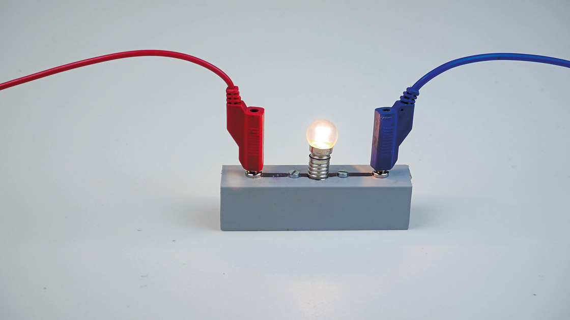 Eine Schaltung mit einer Glühbirne, die über rote und blaue Drähte mit einem grauen Sockel verbunden ist Eine Schaltung mit einer Glühbirne, die über rote und blaue Drähte mit einem grauen Sockel verbunden ist