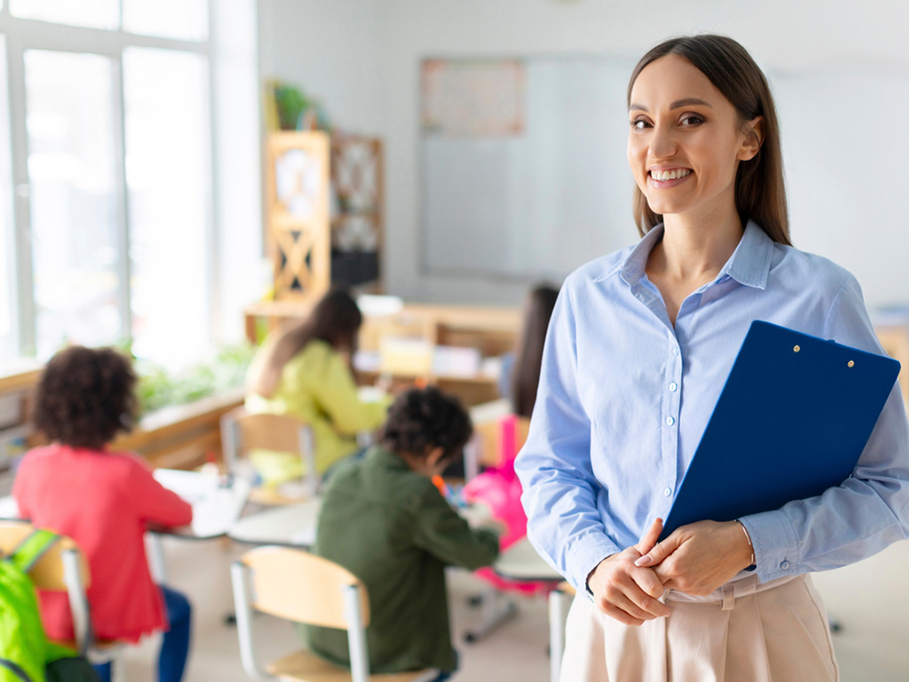 Porträt einer fröhlichen Lehrerin im Klassenzimmer mit Schülern im Hintergrund