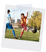 Polaroidfoto, das zwei Jungen beim Fußball spielen zeigt, wobei einer den Ball schießt und der andere im Tor steht