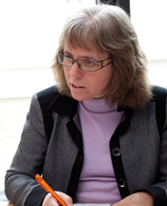Eine Frau mit Brille schreibt mit einem Stift