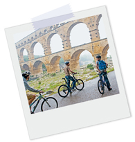 Polaroidfoto von drei Jugendlichen auf Fahrrädern vor einem großen Viadukt